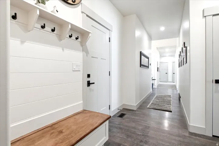 Entryway mudroom featuring a built-in bench with a wood-finish top, white shiplap paneling, and integrated coat hooks