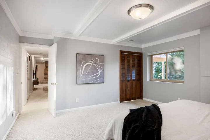 Spacious room featuring light gray walls, white crown molding, and patterned carpeting