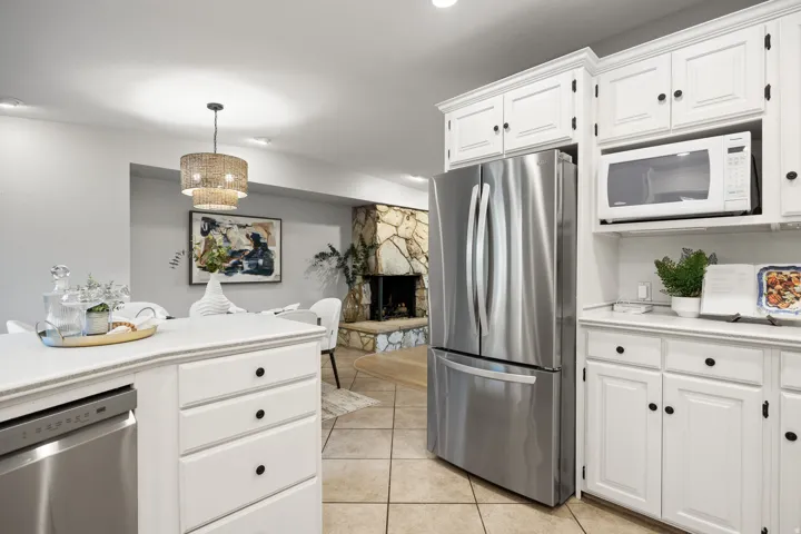 Kitchen featuring white cabinetry with black hardware, stainless steel French-door refrigerator, and integrated microwave
