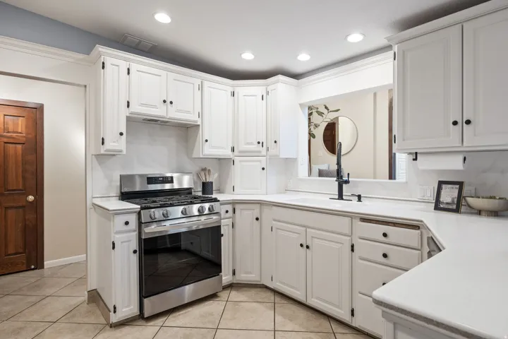 Updated kitchen featuring white shaker-style cabinetry with black hardware, a stainless steel range, and a single-basin sink with a matte black faucet