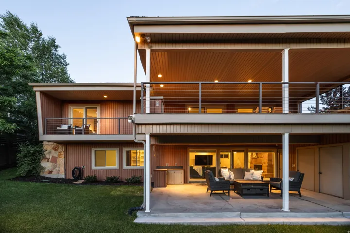 Multi-level exterior featuring wood panel siding, stone accents, and a manicured lawn