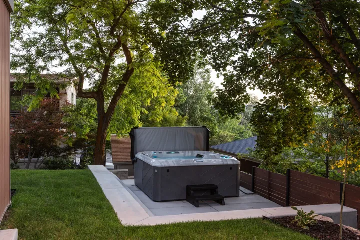Outdoor spa with a grey textured finish, set on a light-toned concrete patio