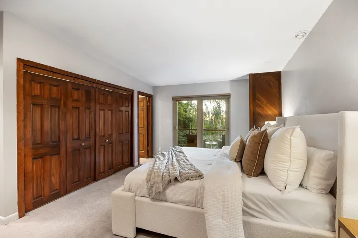 Bedroom featuring wood-finish bi-fold closet doors, light gray wall paint, recessed ceiling lighting, and a wood-paneled accent wall
