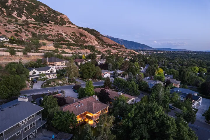 Residential neighborhood with varied architectural styles, mature trees, and mountainous topography