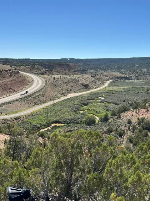 Expansive natural landscape featuring varied terrain, a winding riverbed, and natural foliage