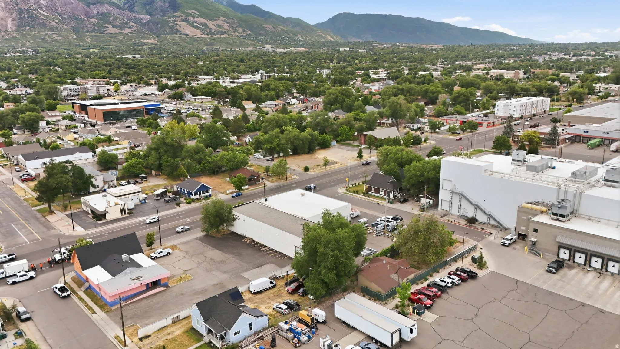 Aerial perspective showcasing a mixed-use neighborhood with commercial properties, residential structures, and established trees