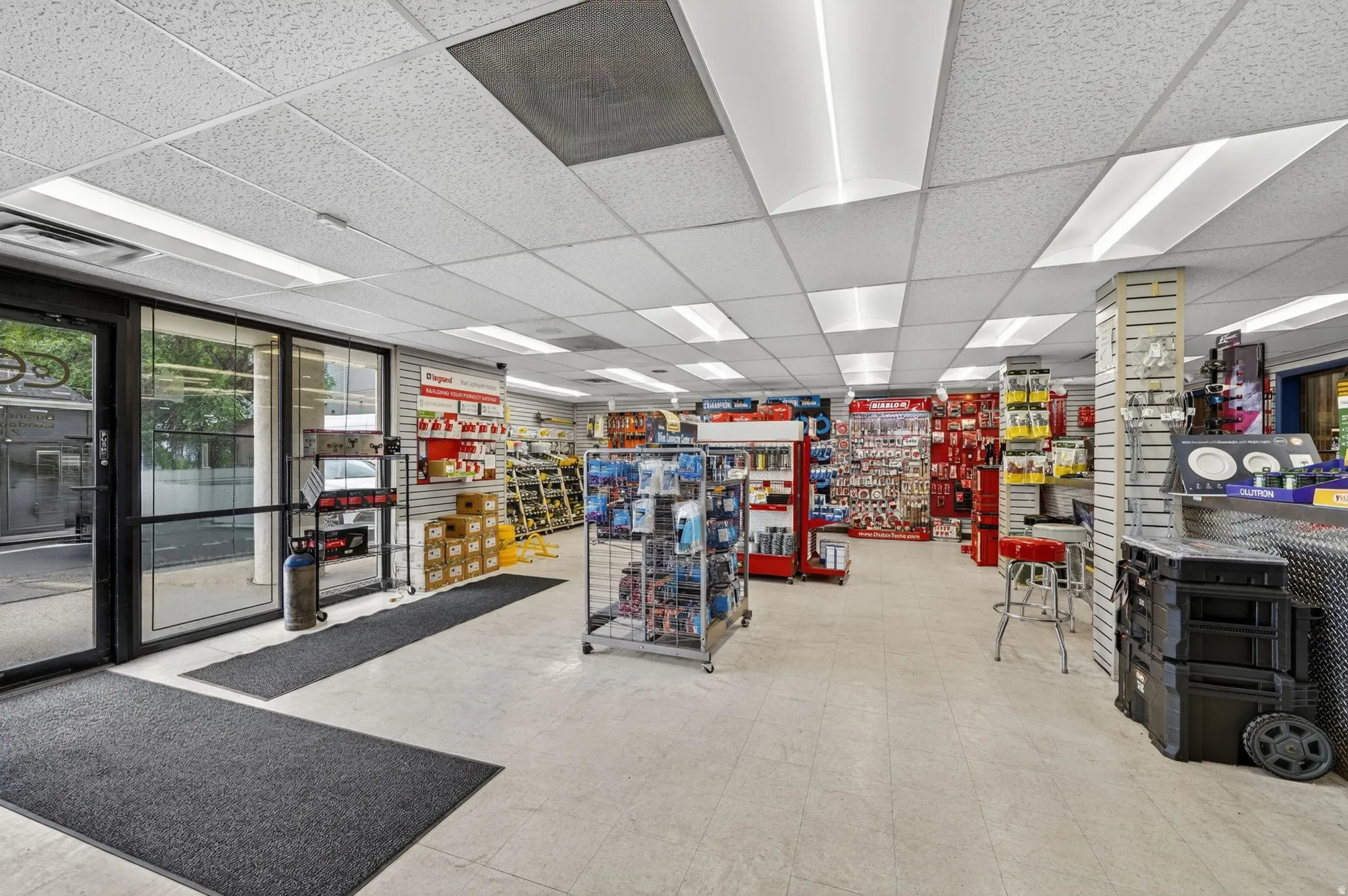 Expansive commercial interior featuring a suspended acoustical tile ceiling with integrated fluorescent lighting panels