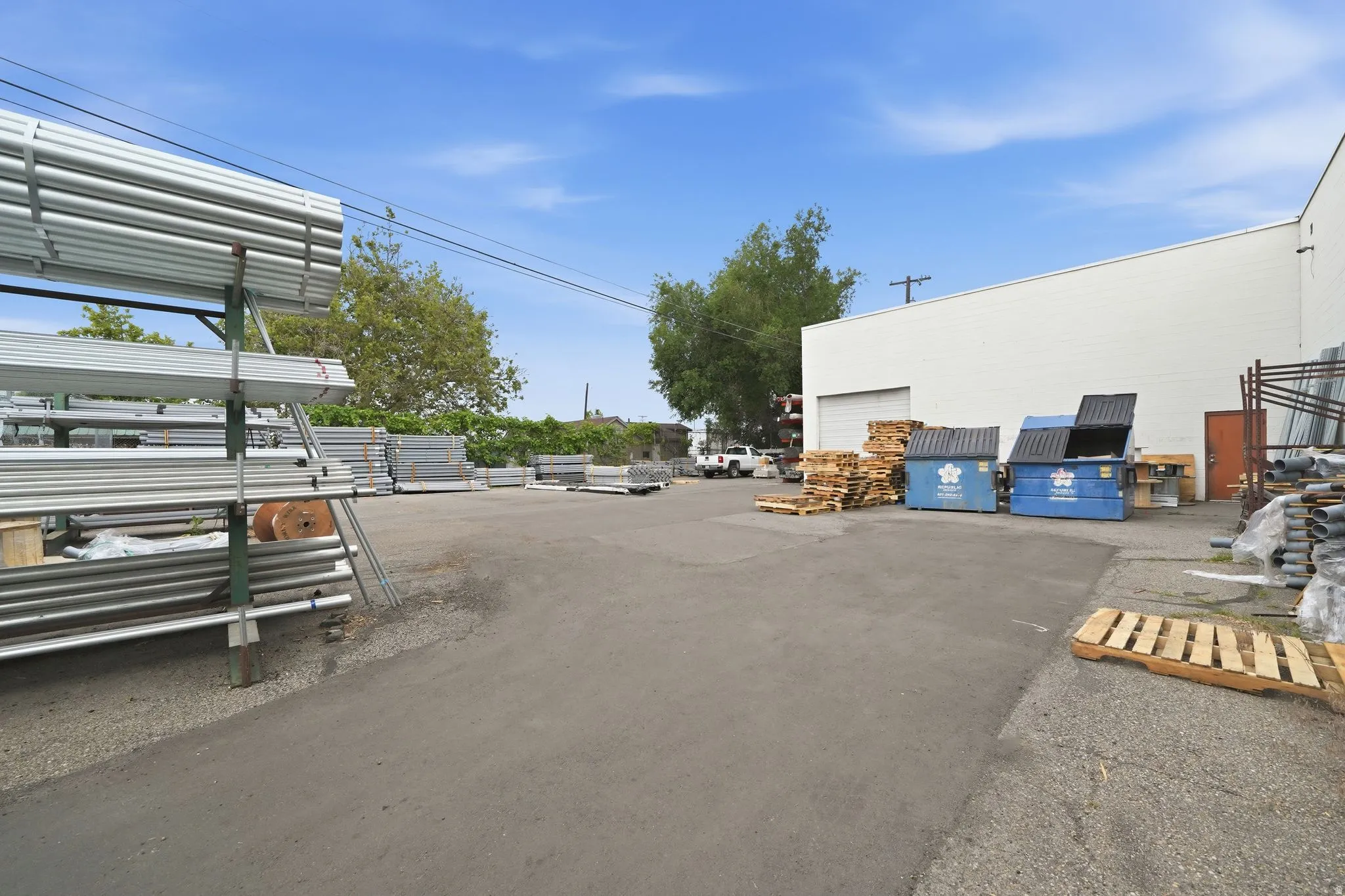 Paved outdoor area featuring a white industrial building with a roll-up door