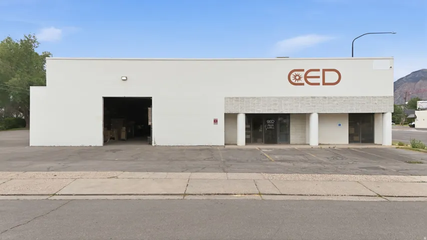 Commercial building featuring a white painted brick exterior and asphalt parking lot