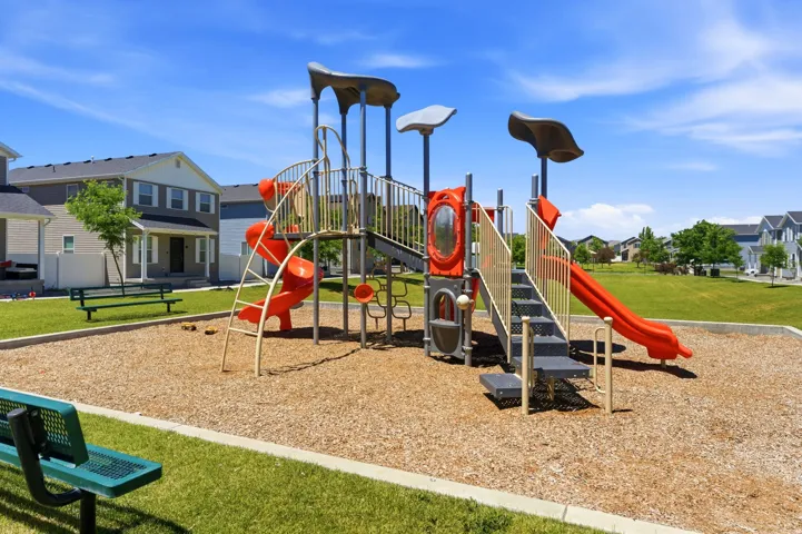 Community playground featuring multi-level play structures, slides, ladders, and protective wood chip surfacing