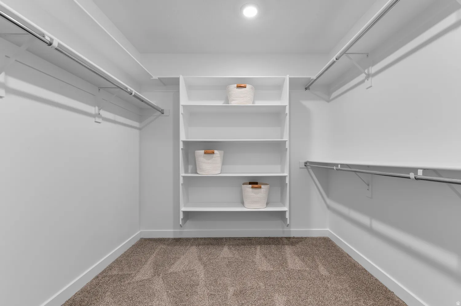Walk-in closet featuring built-in shelving, multiple hanging rods, recessed ceiling lighting, white walls, and carpet flooring