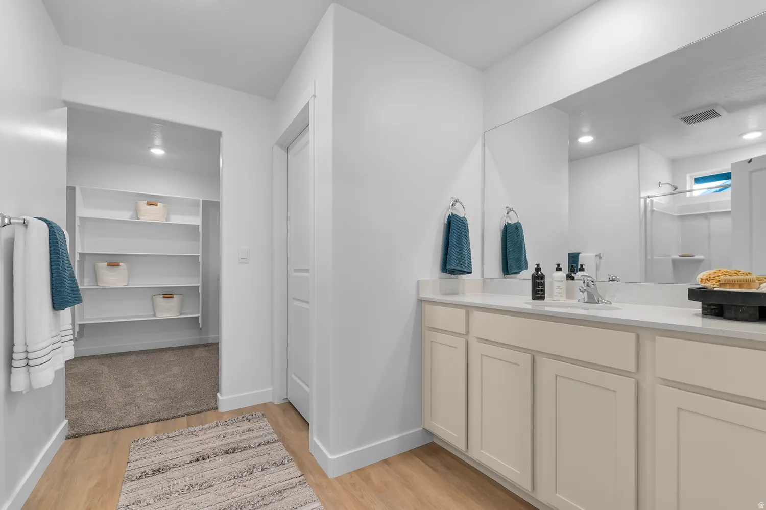 Bathroom vanity with light-colored cabinetry, integrated sink, and a large mirror
