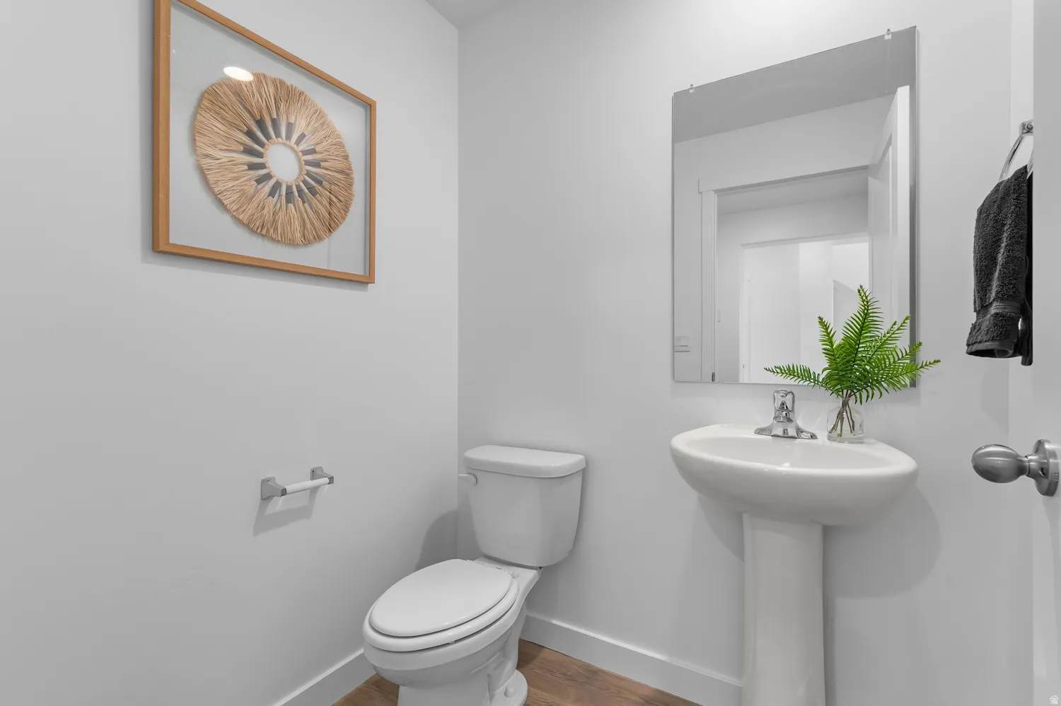 Powder room featuring a pedestal sink, chrome-finish faucet, and a wall-mounted mirror