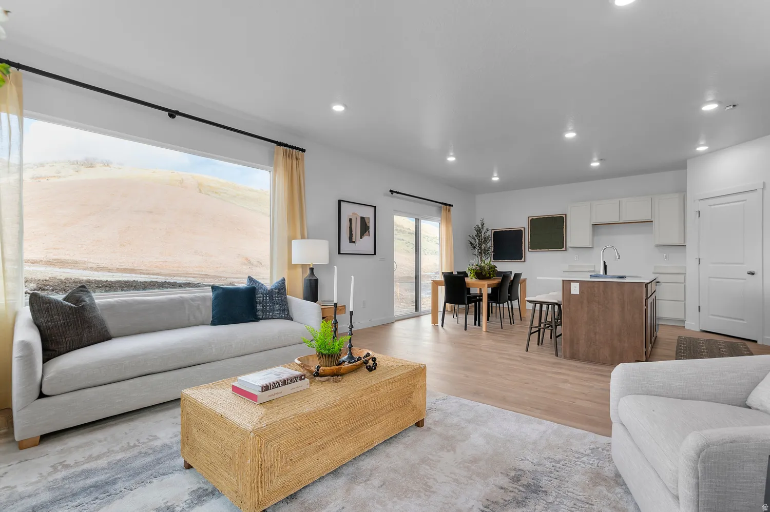 Open-concept living area featuring a wide picture window, recessed lighting, and wood-finish flooring