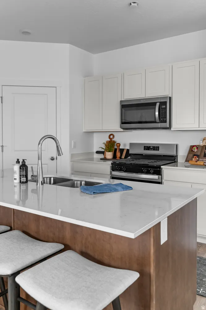 Kitchen featuring white shaker-style cabinetry, a stainless steel microwave, and a stainless steel gas range
