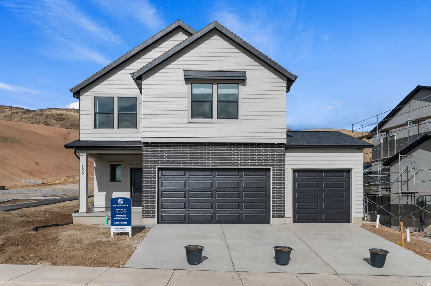 Contemporary two-story residence featuring light gray siding and dark gray brick accents