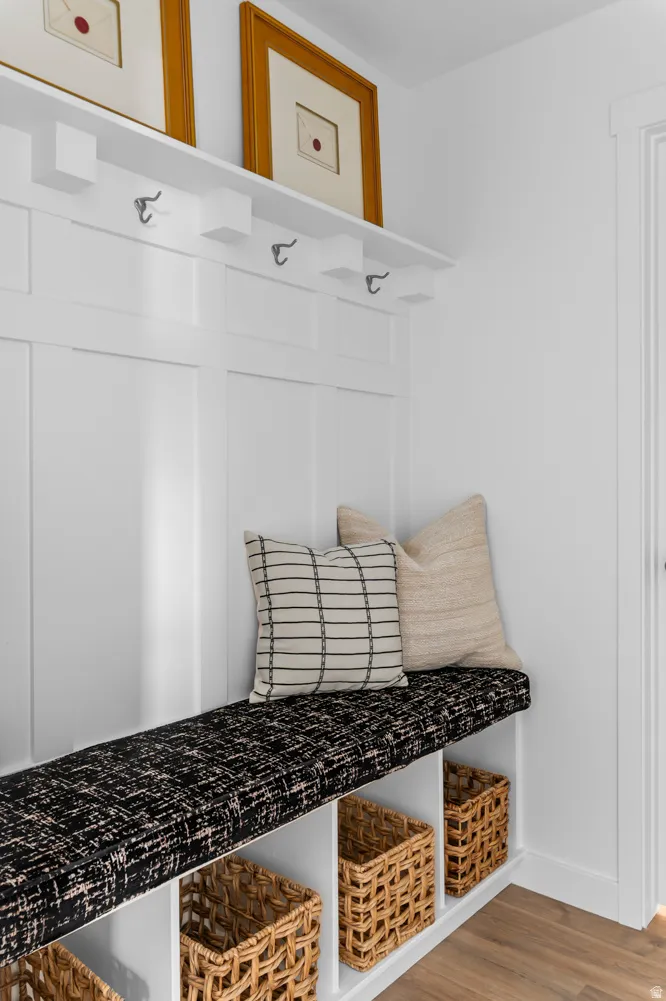 Built-in mudroom bench featuring a patterned cushion, integrated storage cubbies, and overhead shelving with wall-mounted hooks