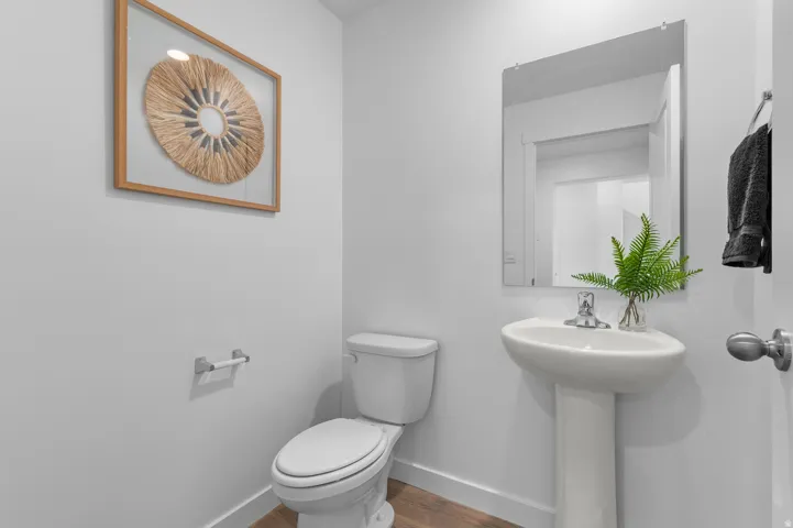 Powder room featuring a pedestal sink, chrome-finish faucet, and a wall-mounted mirror