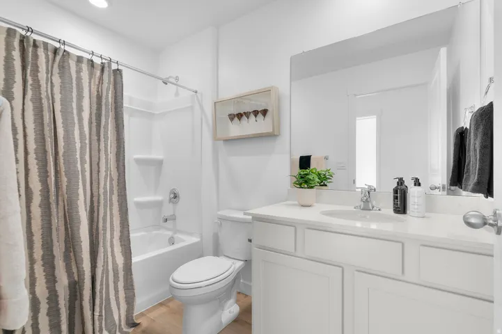 Bathroom featuring a single vanity with stone-finish countertop, undermount sink, and chrome faucet