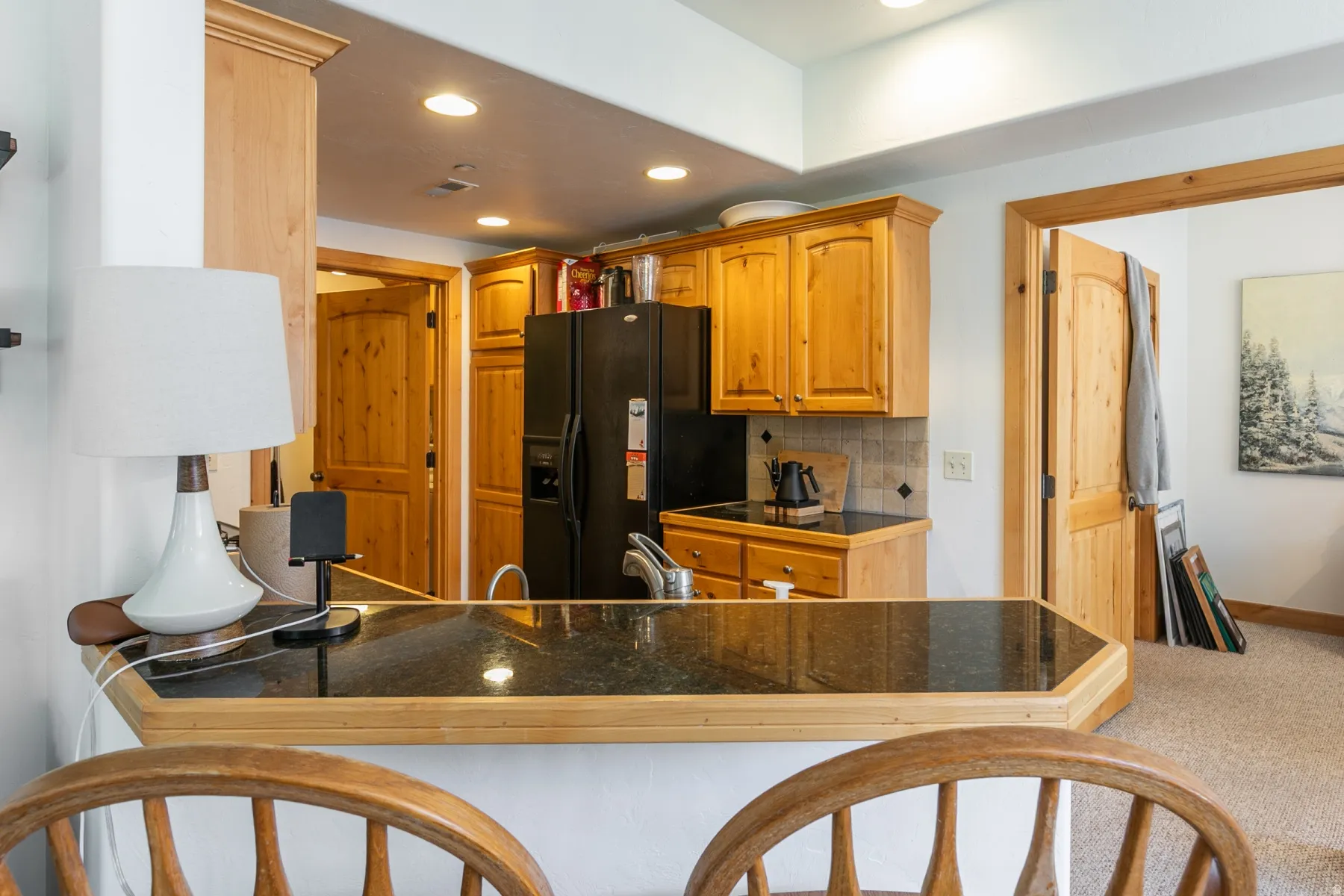 Kitchenette featuring wood cabinetry, dark countertops, a tile backsplash, and recessed lighting