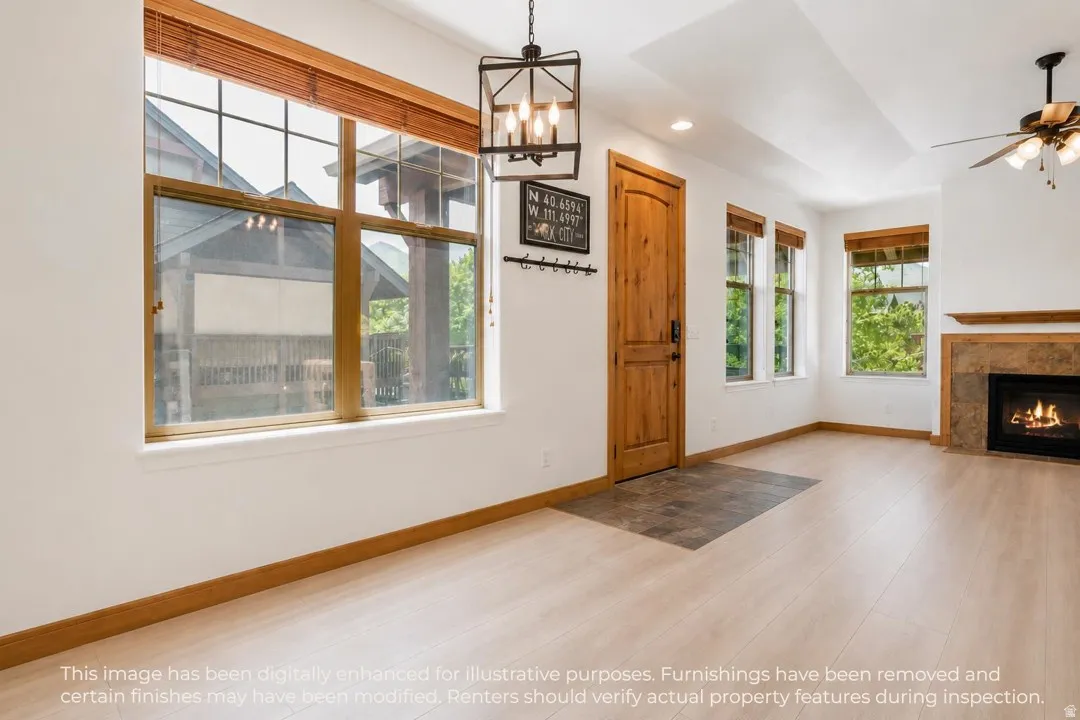 Bright living space featuring wood-finish flooring, a natural wood entry door, and large windows with natural wood blinds