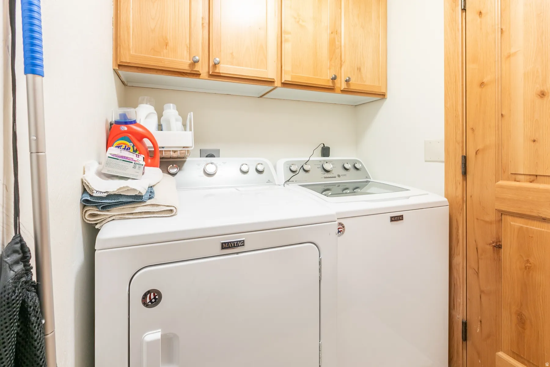 Dedicated utility space featuring overhead wood cabinetry and a wood-panel door