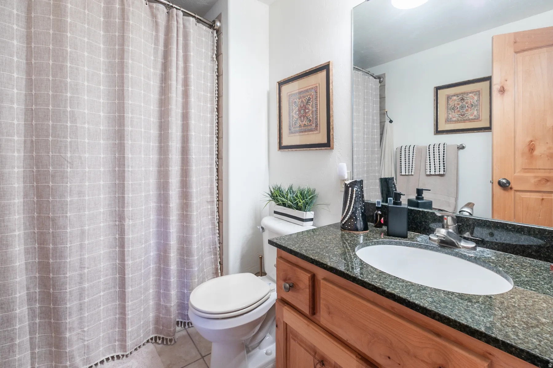 Bathroom featuring a wood-finish vanity with an integrated oval sink, stone-finish countertop, and tile flooring