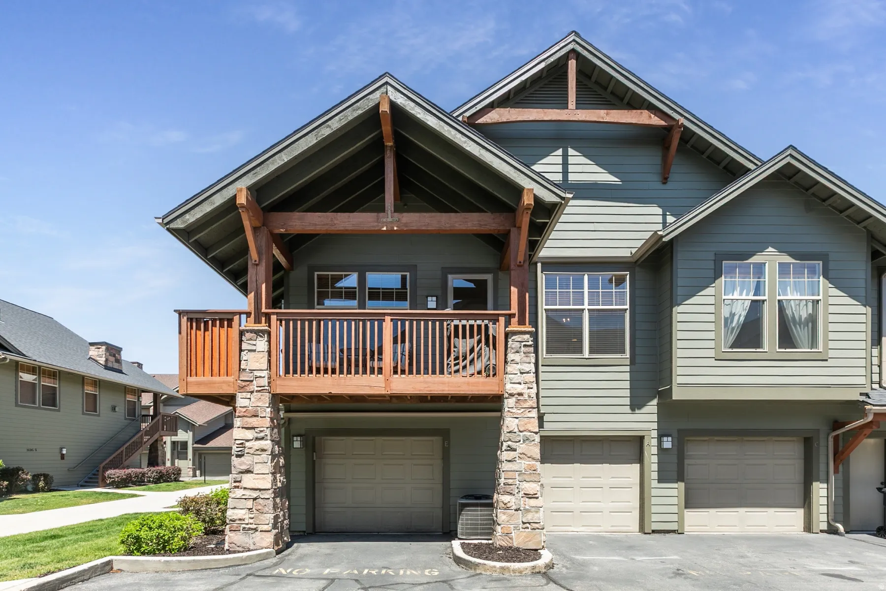 Multi-level exterior featuring a private balcony with wood railings and exposed wood beams