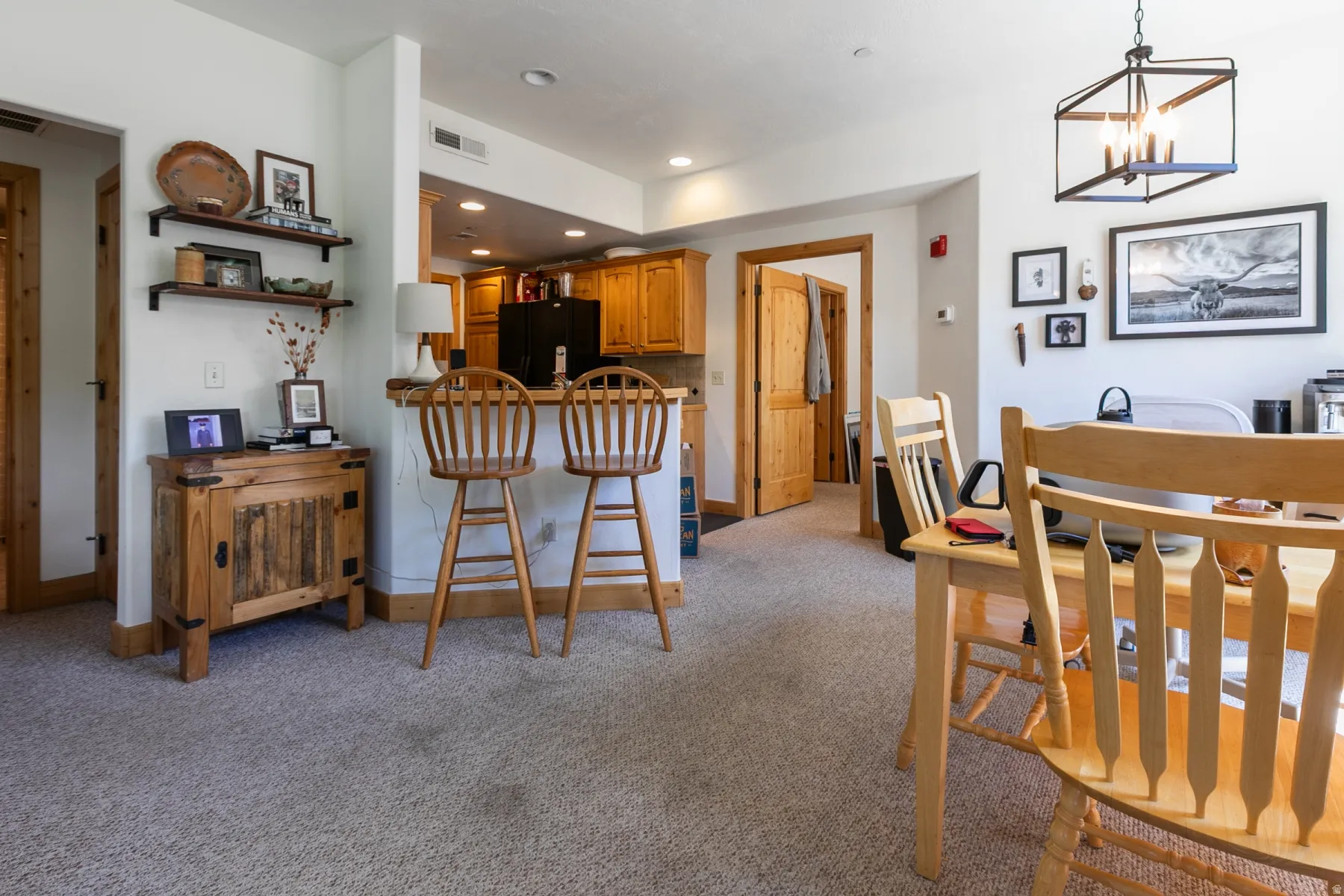 Open-concept living area with carpet flooring and warm wood-finish trim