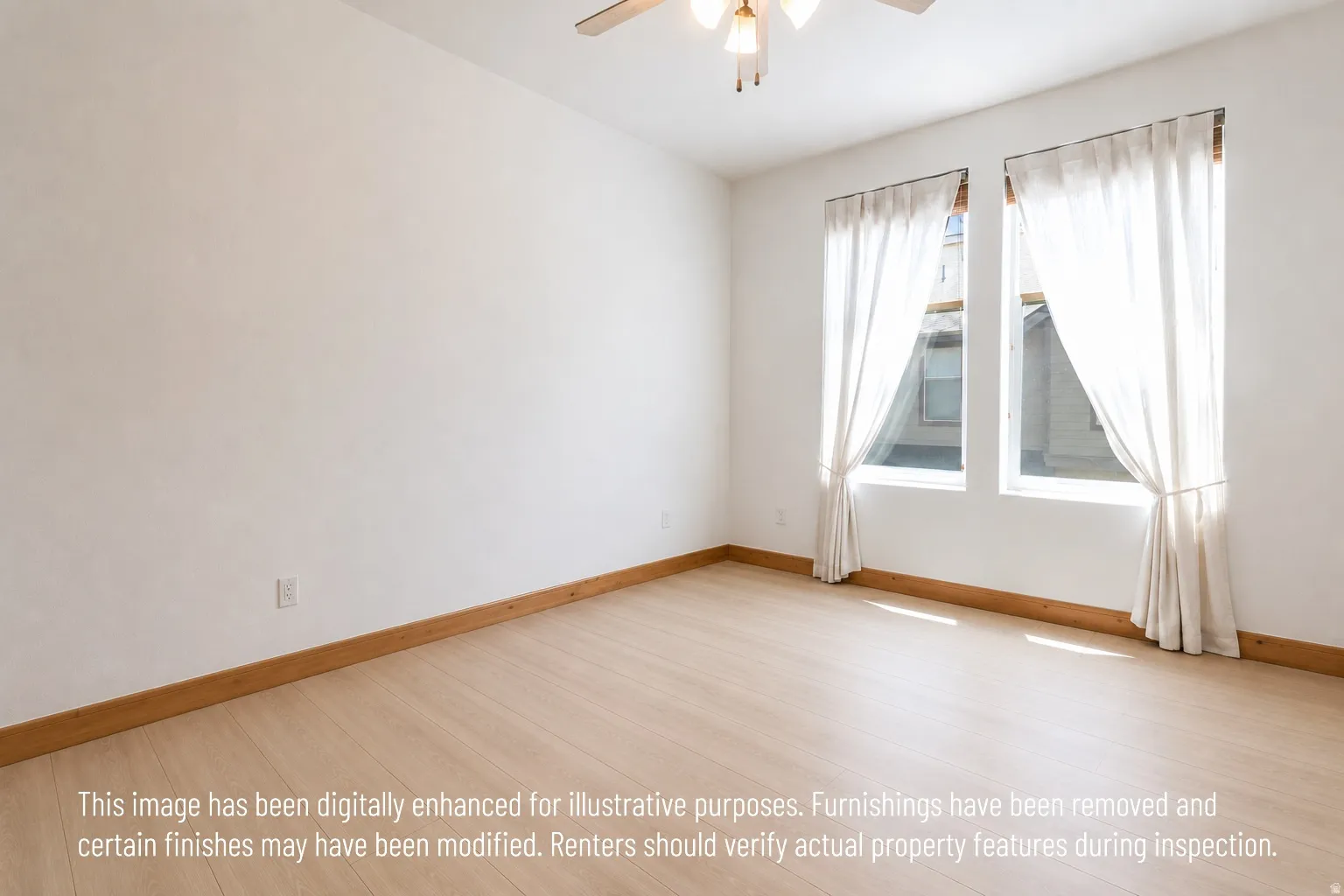 Bright room featuring two windows with sheer curtains, wood-finish flooring, and a ceiling fan with integrated lighting