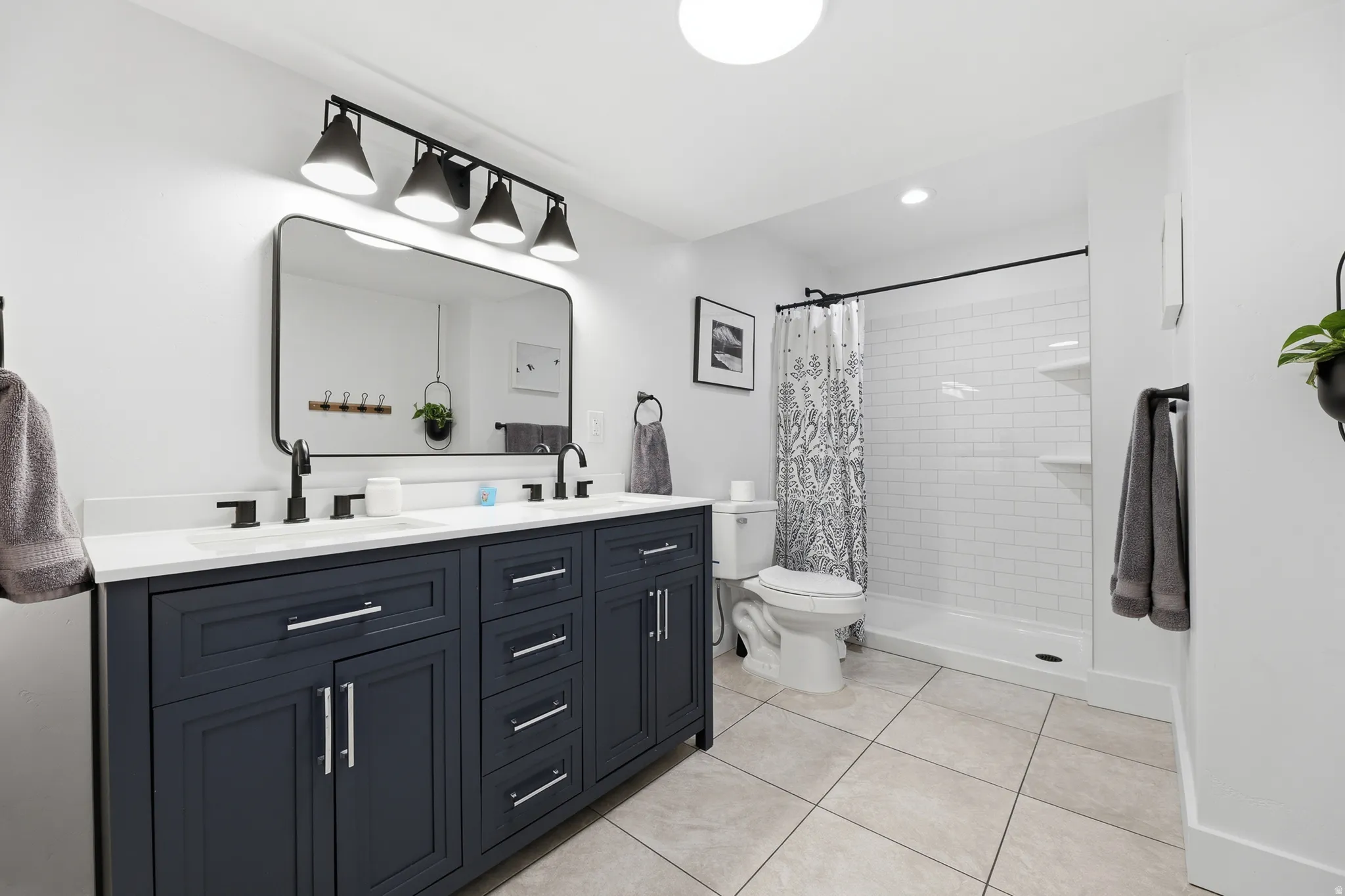 Bathroom featuring a dual vanity with a dark blue cabinet, white countertop, and rectangular undermount sinks