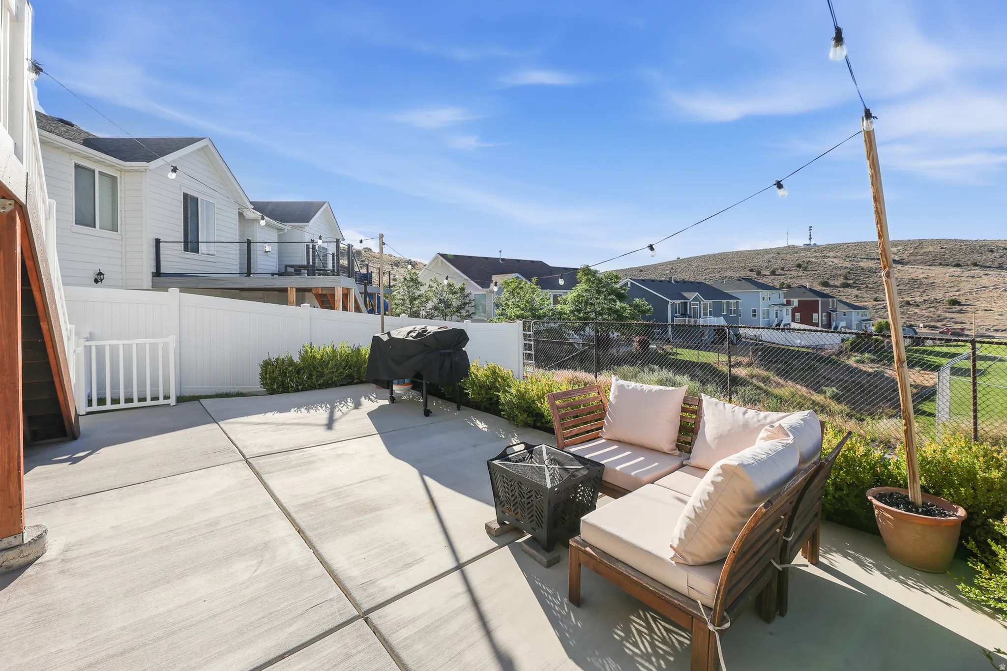Expansive concrete patio area with a white privacy fence and manicured shrubbery