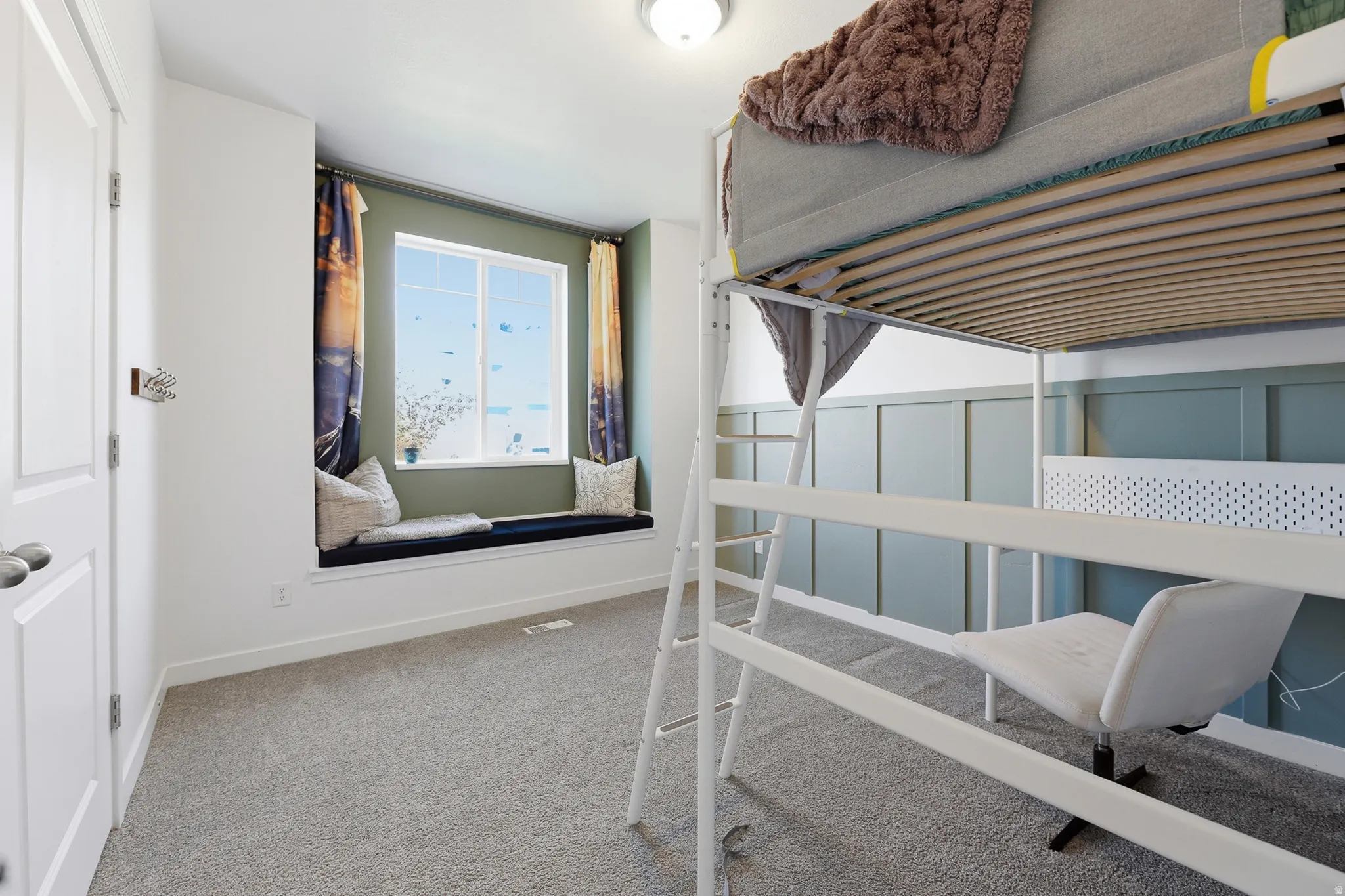 Recessed window bench with a built-in cushion, white trim, and a paneled accent wall
