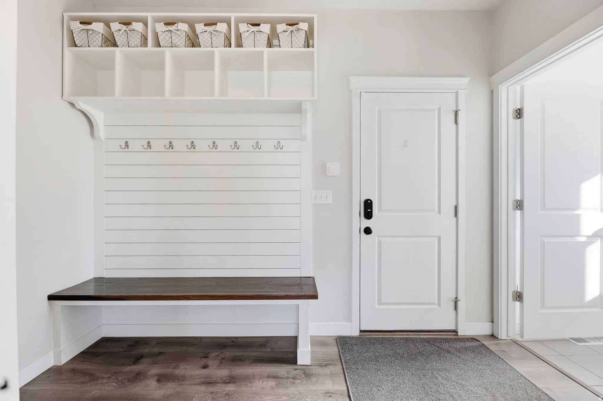 Built-in mudroom bench with dark wood-finish top, white shiplap-style backing, and upper cubby storage