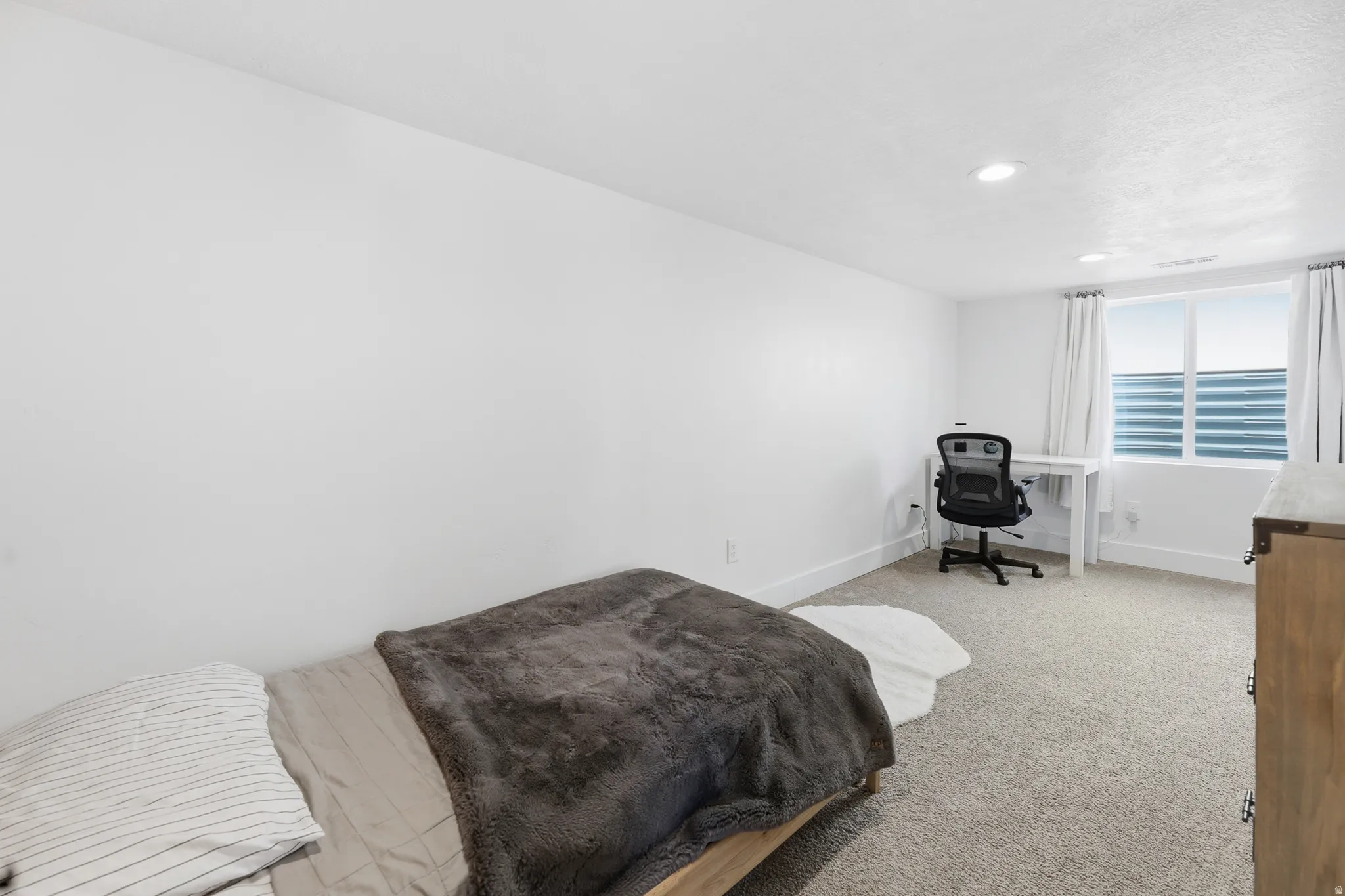 Spacious room featuring neutral carpet flooring, recessed lighting, and a window with blinds