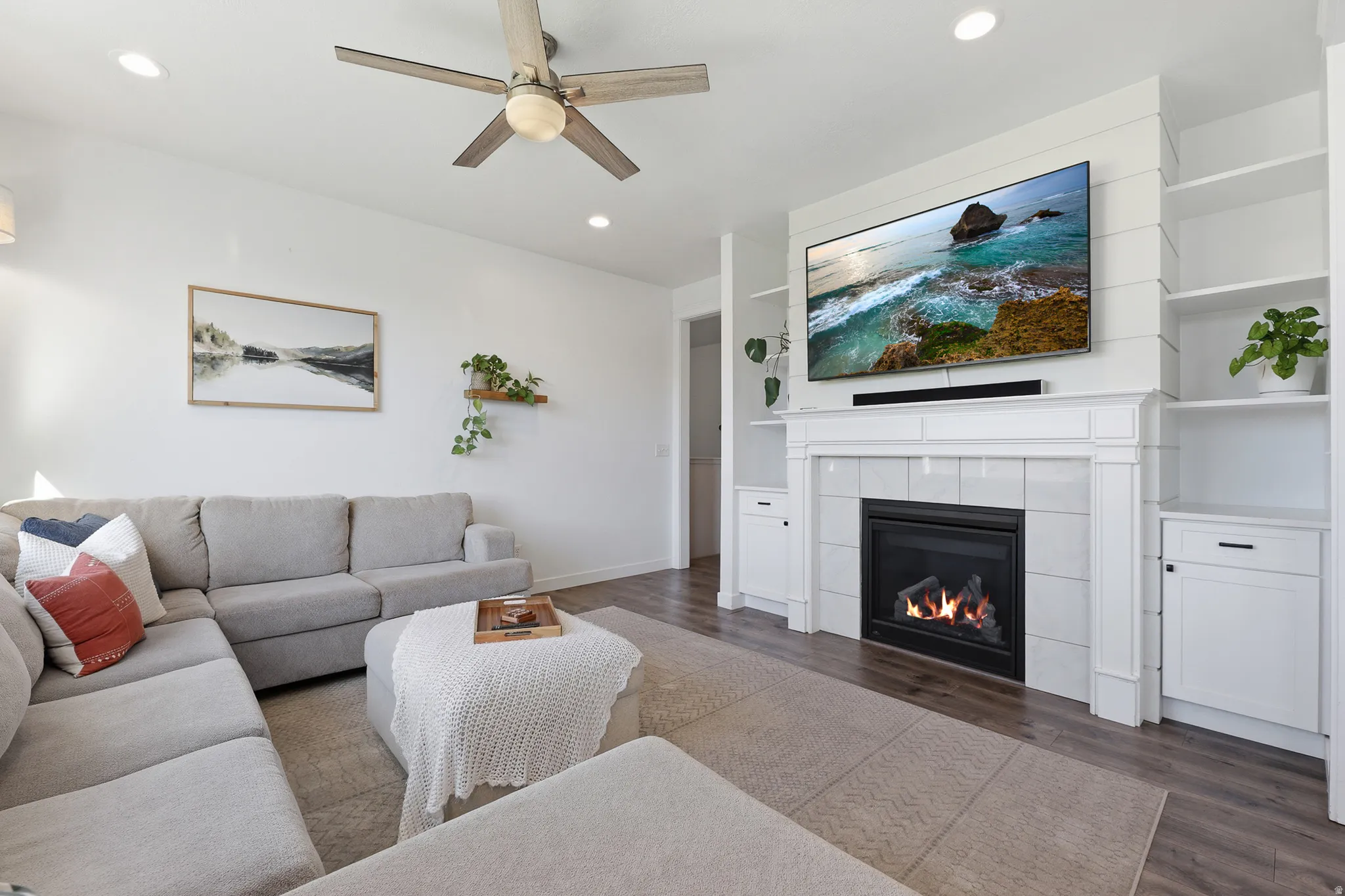 Living area featuring a central fireplace with a shiplap accent wall, built-in shelving, and wood-finish flooring
