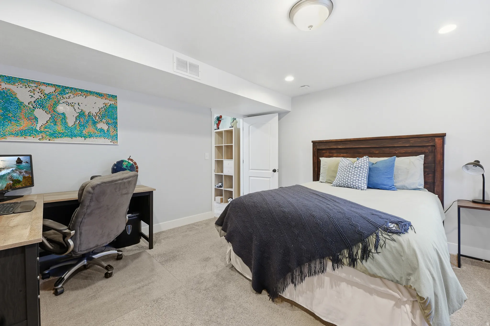 Carpeted room featuring a dark wood-finish headboard, a white painted door with dark hardware, a light wood-finish desk, recessed ceiling lighting, and a semi-flush mount ceiling fixture