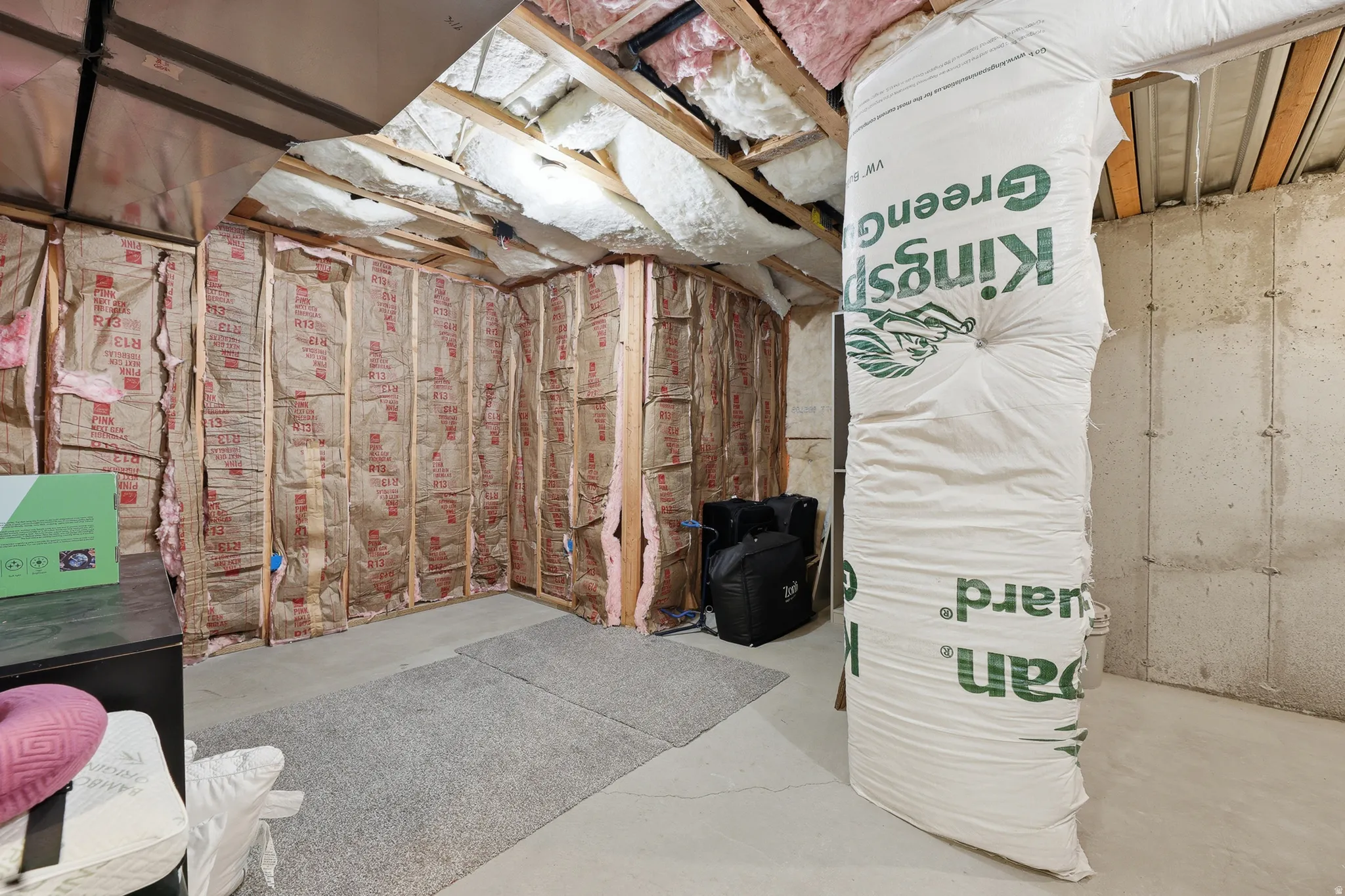 Unfinished basement area featuring exposed wood framing, concrete foundation walls, and insulation