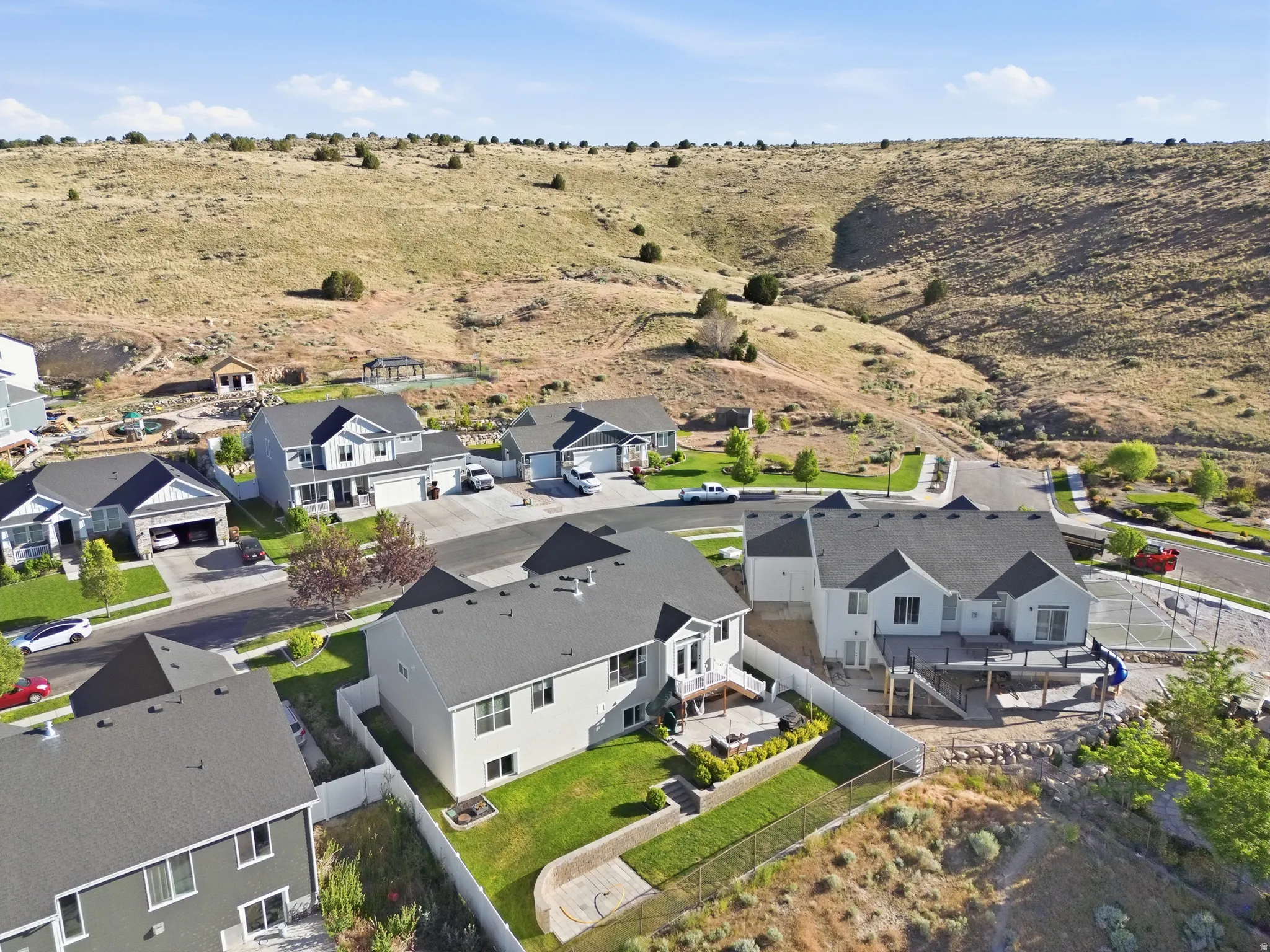 Contemporary residence with a multi-level deck, fenced backyard, and surrounding natural landscape