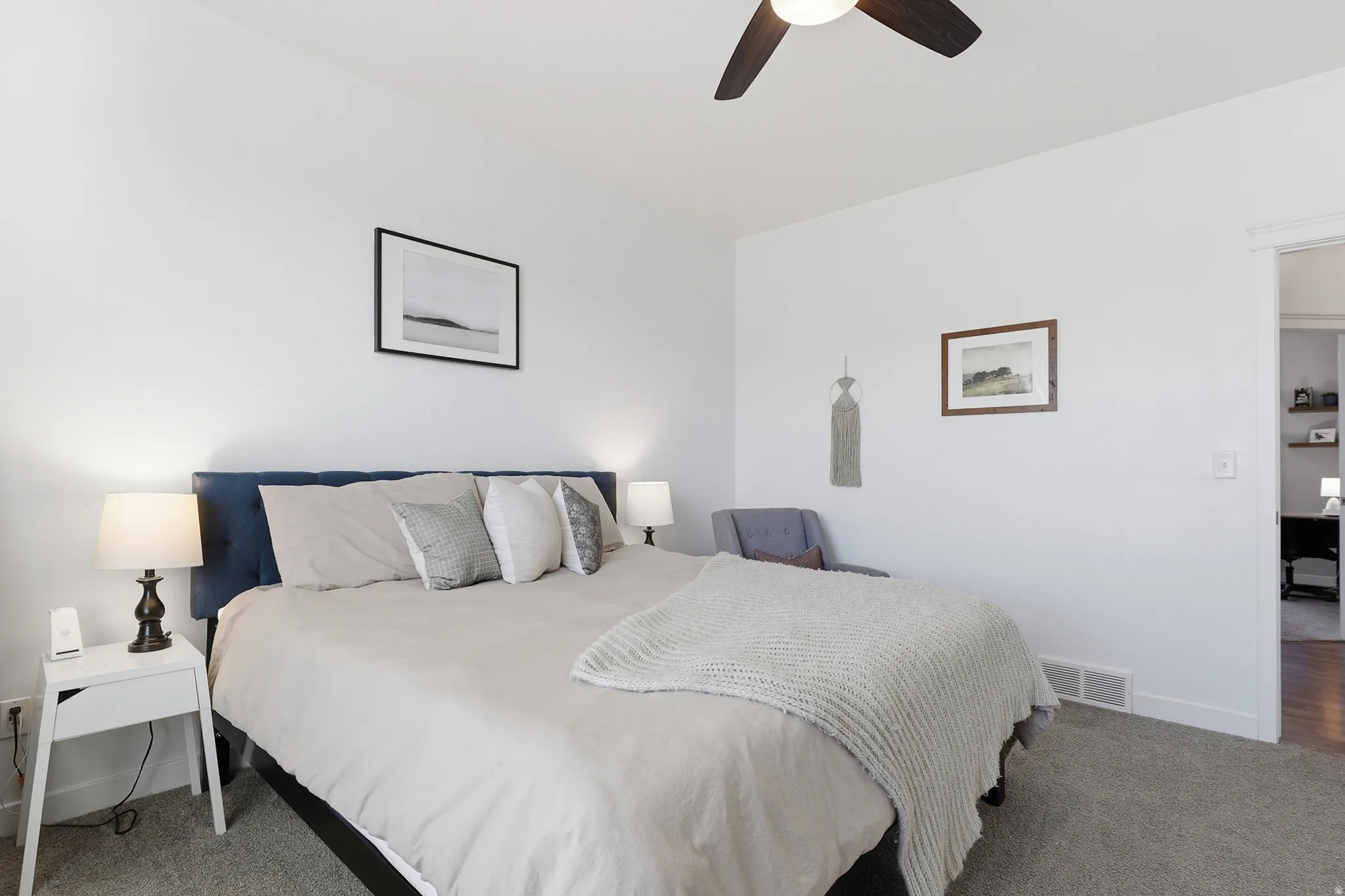 Carpeted bedroom featuring a dark wood-finish ceiling fan and white walls