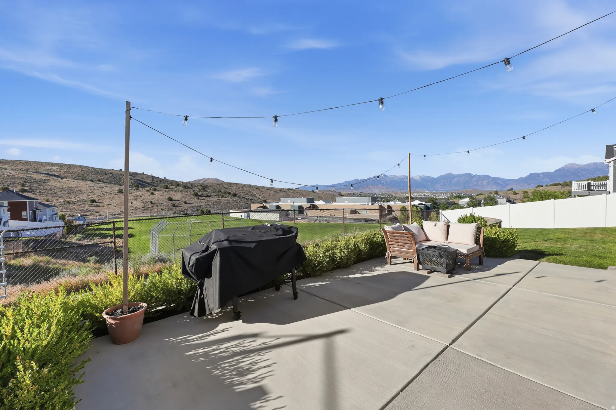 Concrete patio with string lighting, green lawn, and distant mountains