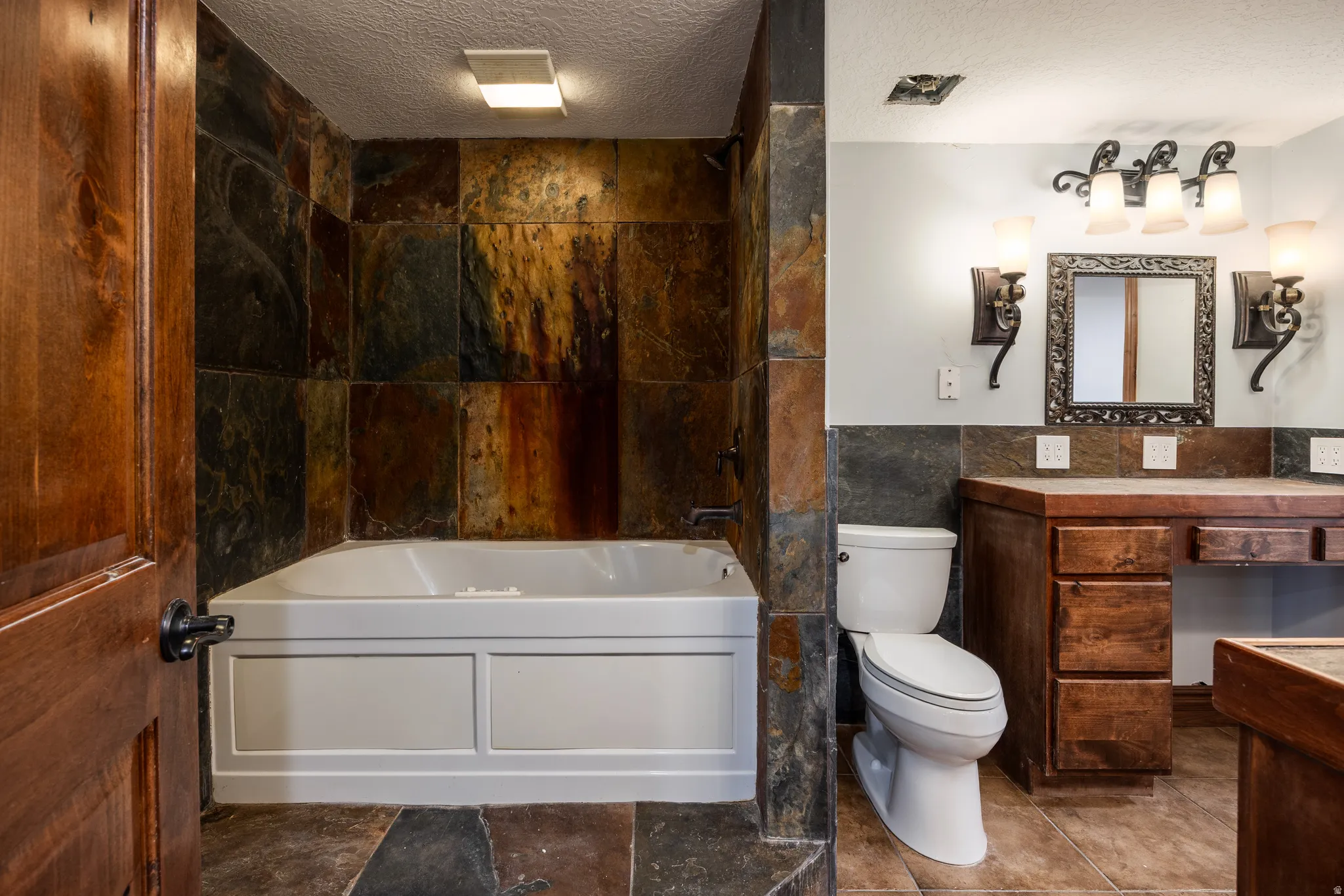 Deep soaking tub surrounded by natural stone tile