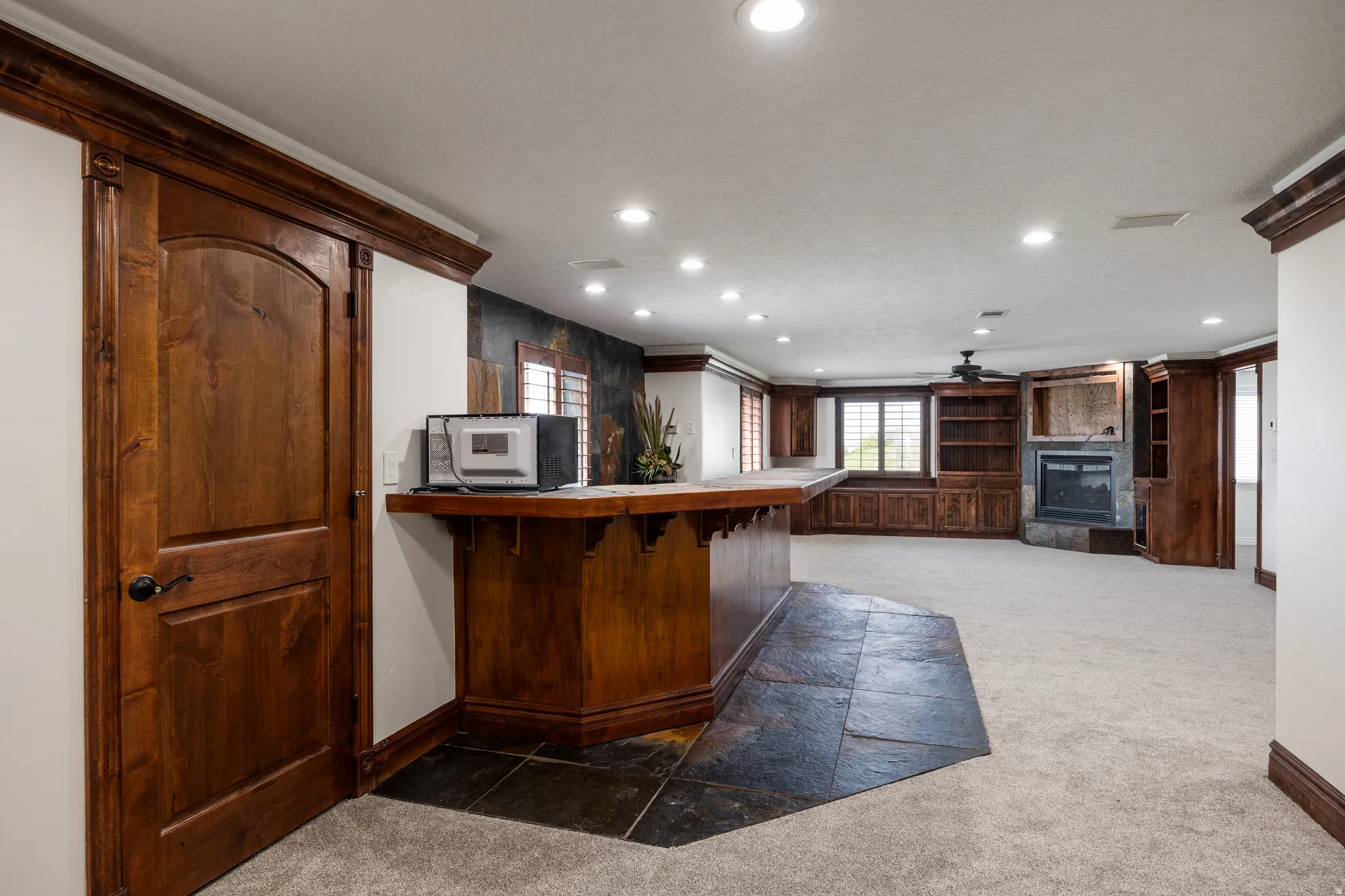 Built-in bar with dark wood cabinetry and stone tile flooring