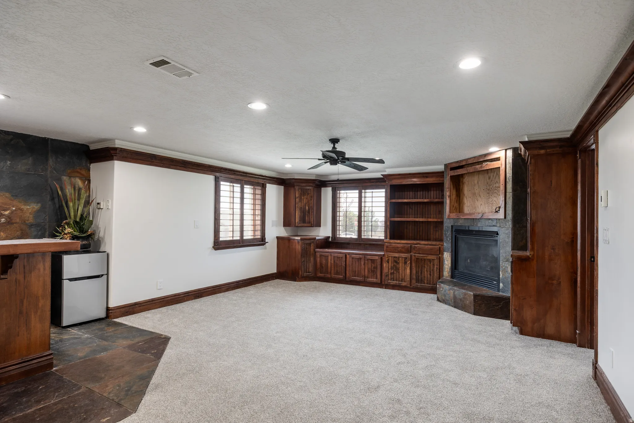 Recessed lighting, ceiling fan, built-in shelving, stone fireplace with hearth, and plantation shutters
