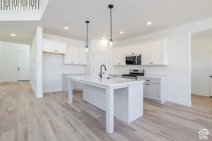 Kitchen featuring wood-finish flooring, quartz countertops, a central island, dual-tone cabinetry, and matte black plumbing fixtures