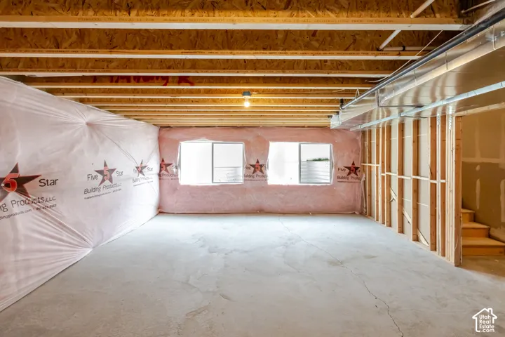 Unfinished lower level featuring exposed wood-joist ceiling, concrete floor, dual egress windows, and thermal wall insulation