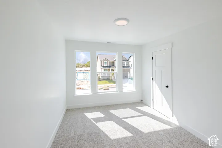 Neutral-toned wall-to-wall carpeting, three-panel window assembly, recessed ceiling lighting, and a multi-panel door with matte black hardware
