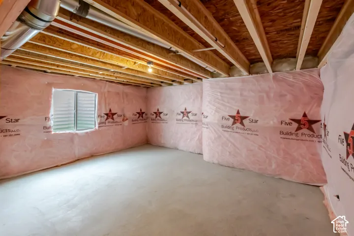 Unfinished lower level featuring exposed wood joist ceilings, concrete flooring, insulated wall barriers, and a singular egress window