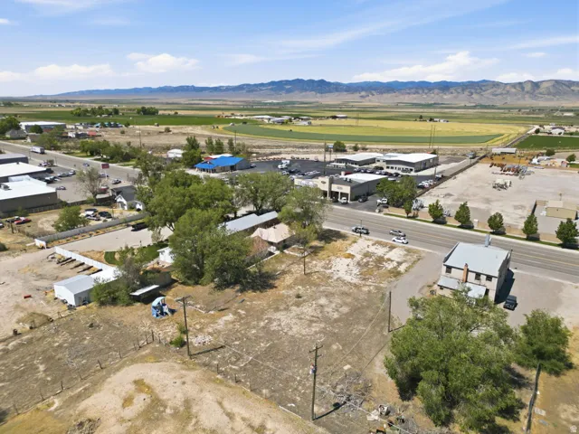 Aerial perspective featuring extensive undeveloped land, a primary road frontage, and distant mountainous scenery