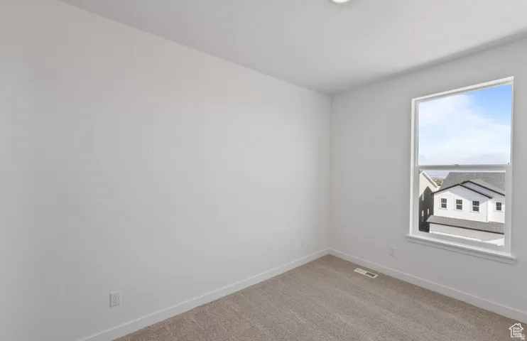 Bright room featuring neutral carpeting, white walls, and a large window with white trim